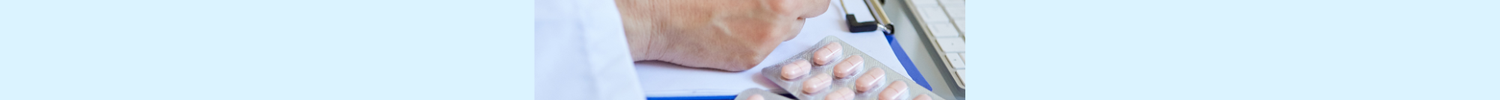 Eine schreibende Hand neben der Tabletten liegen.
